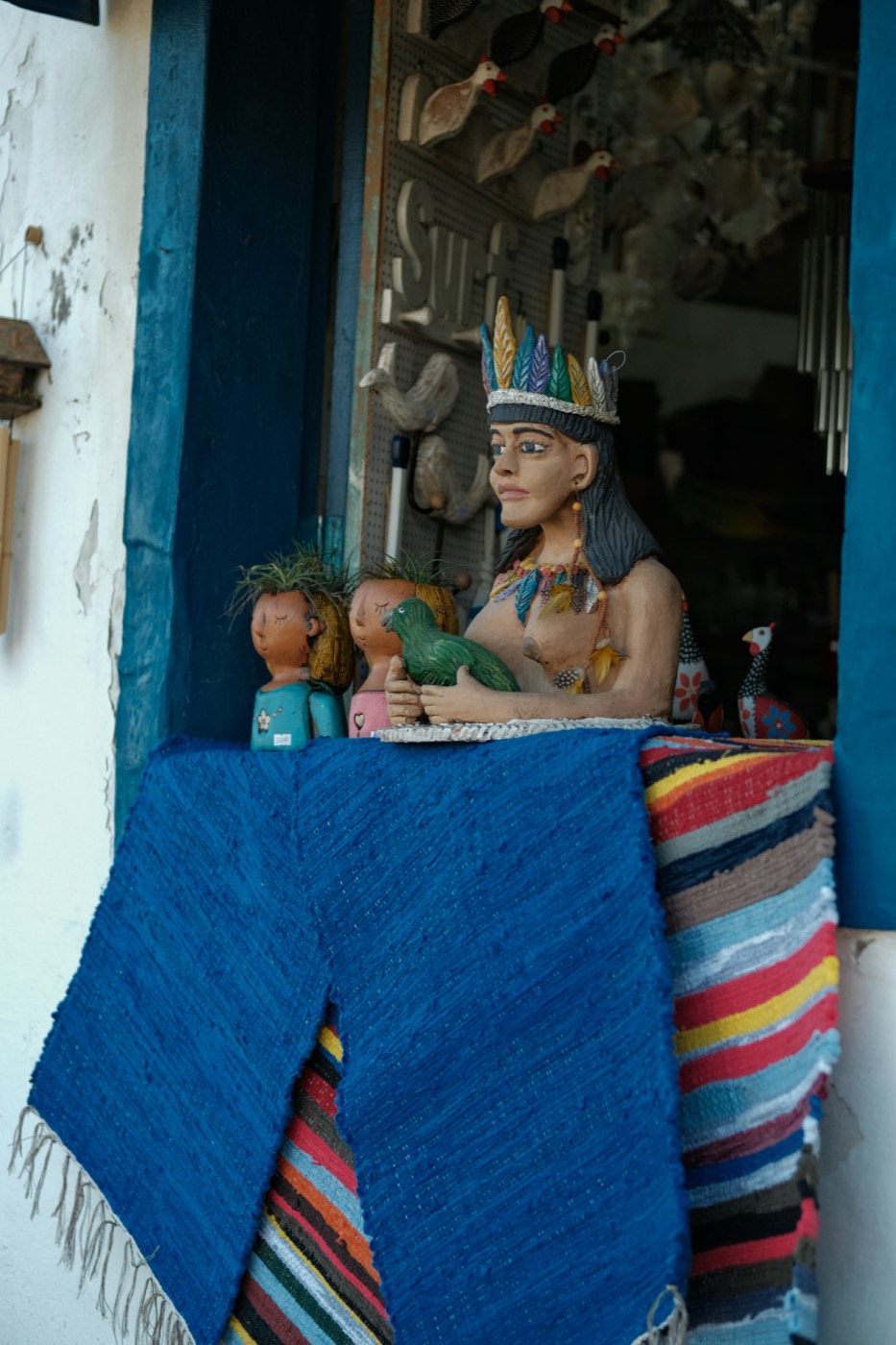 Talla en madera de una figura tradicional sobre tapetes tejidos en la ventana de un taller